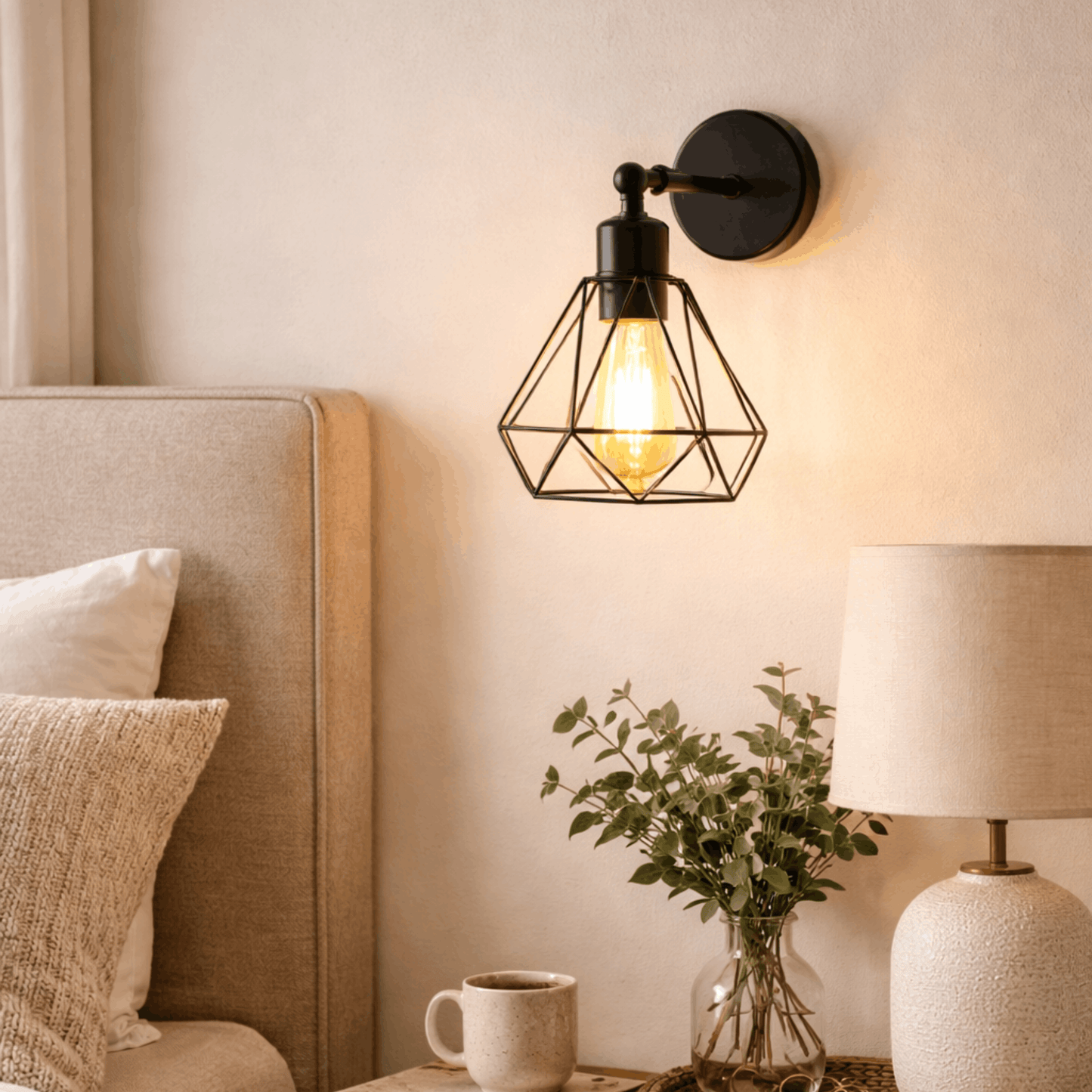 Zwarte wandlamp met metalen kooi en warme lichtbron, geplaatst naast een bed in een slaapkamer voor sfeervolle verlichting.