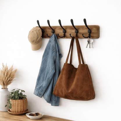 Houten wandkapstok met vijf zwarte metalen haken, gebruikt voor het ophangen van jas, tas, pet en sleutels aan de muur in de hal.