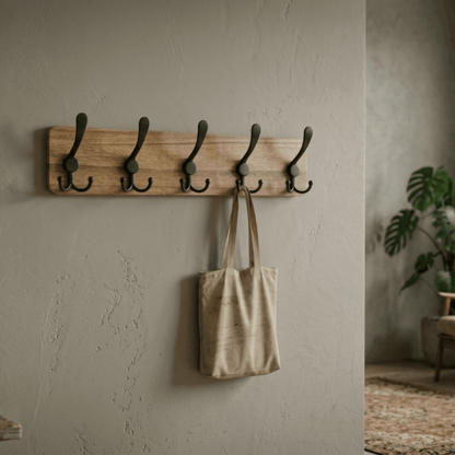 Minimalistische houten wandkapstok met vijf zwarte haken boven een bankje in de hal, ideaal voor jassen en accessoires.