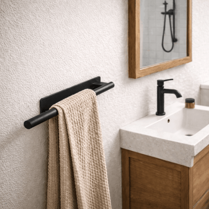 Modern zwart handdoekenrek voor wandmontage met beige handdoek, geplaatst naast een wastafel in een stijlvolle badkamer.