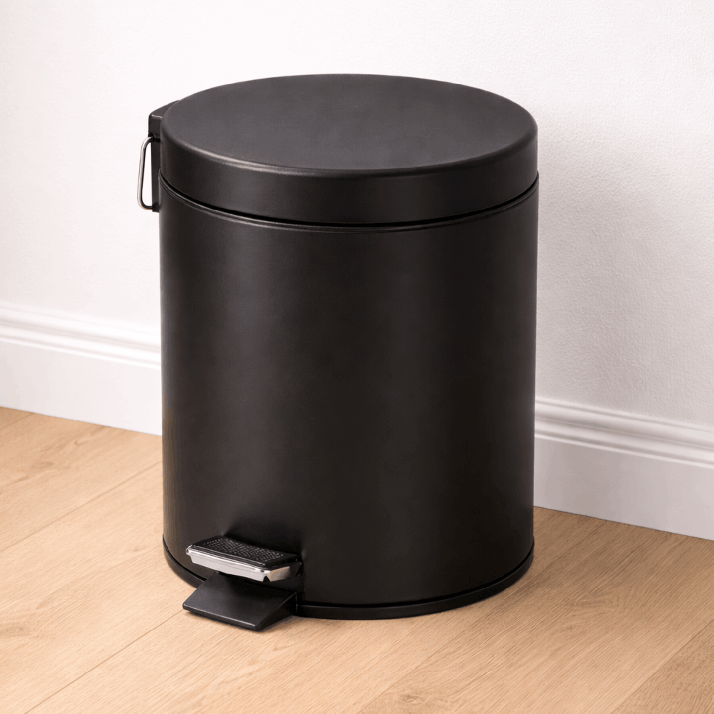 Zwarte cilindrische prullenbak met pedaal en deksel, ideaal voor gebruik in keuken, badkamer of kantoor.
