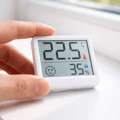 Compacte digitale hygrometer met display, toont temperatuur van 22,5 graden en luchtvochtigheid van 35 procent, vastgehouden in de hand.