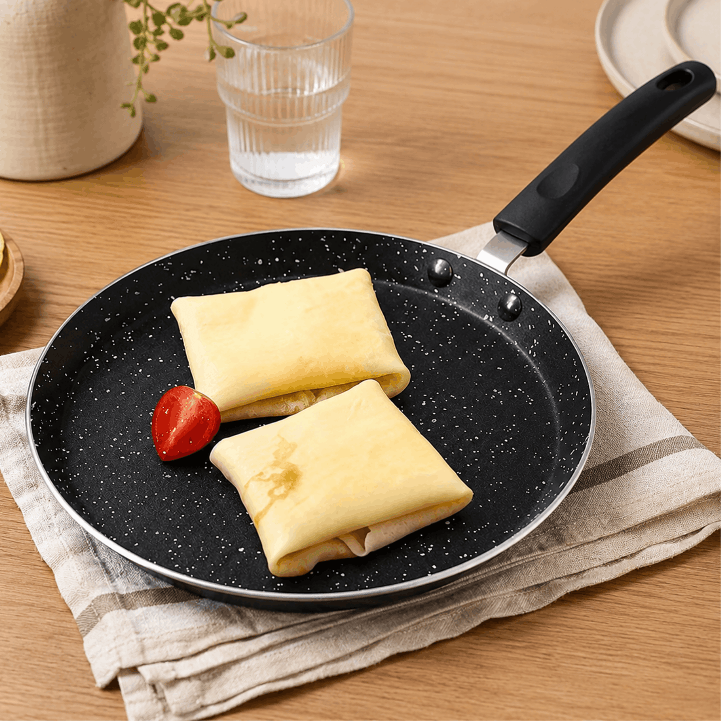 Twee gevulde pannenkoeken in een zwarte pannenkoekpan op een houten tafel.