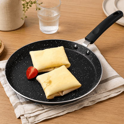 Twee gevulde pannenkoeken in een zwarte pannenkoekpan op een houten tafel.