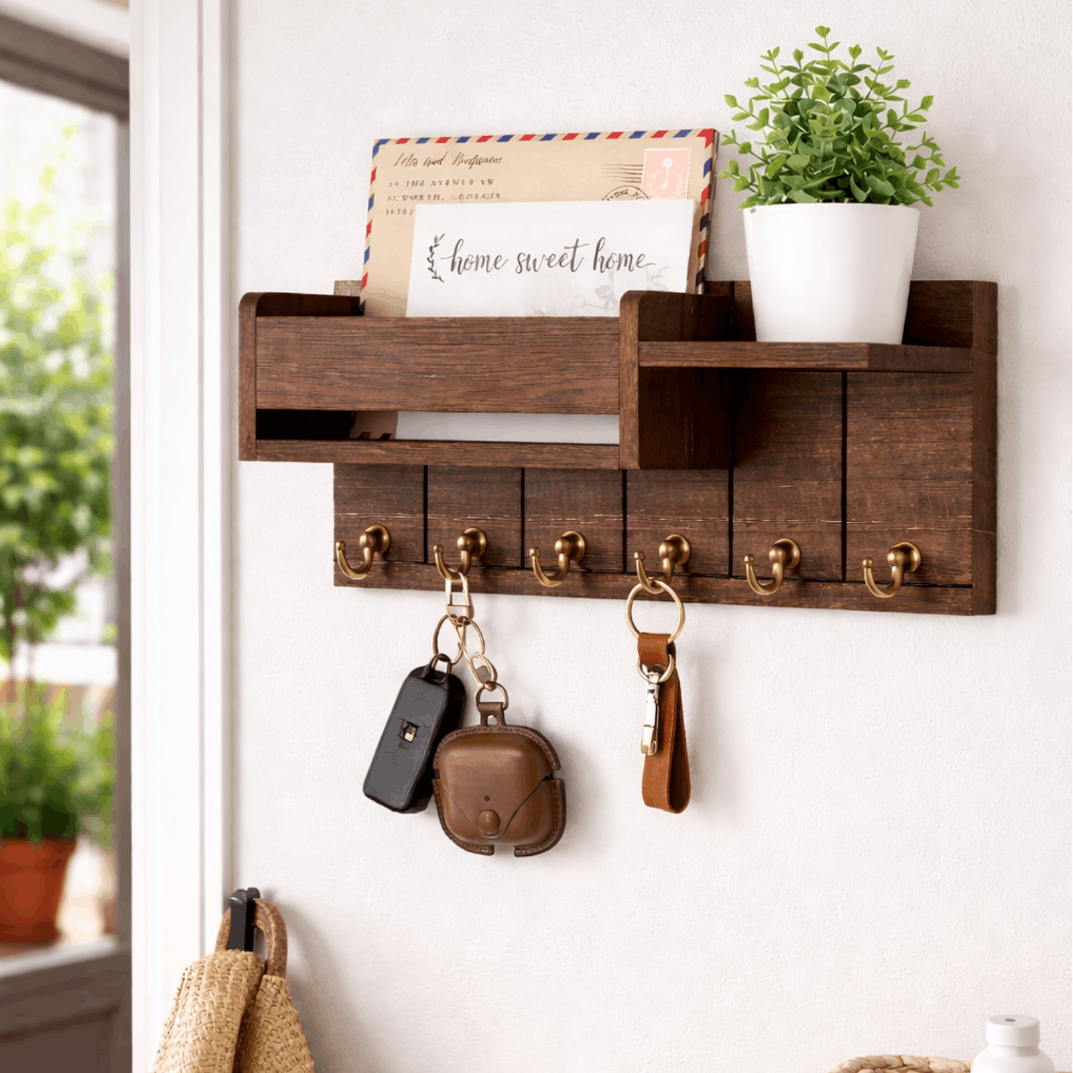 Houten wandrek met sleutelhaken en brievenvak, met sleutels en plantje aan een lichte muur.