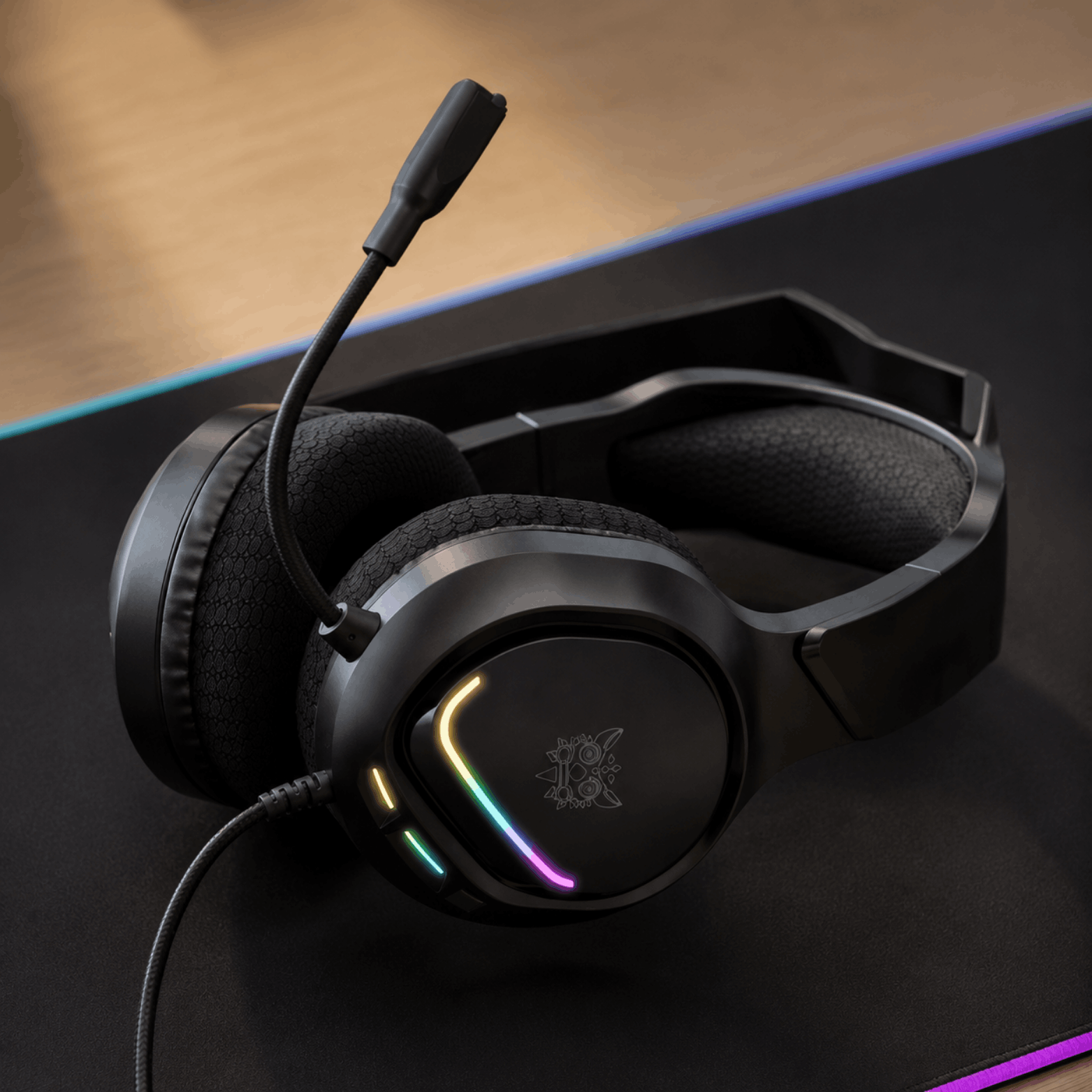 Zwarte koptelefoon met microfoon en RGB-verlichting liggend op een muismat.