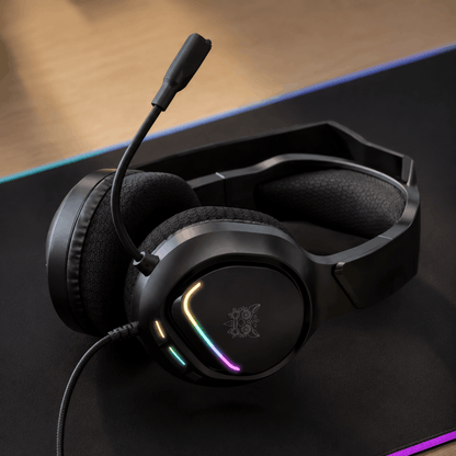 Zwarte koptelefoon met microfoon en RGB-verlichting liggend op een muismat.