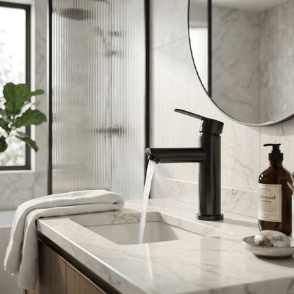 Moderne zwarte badkamerkraan voor warm en koud water, gemonteerd op een marmeren wastafel in een stijlvolle badkamer.