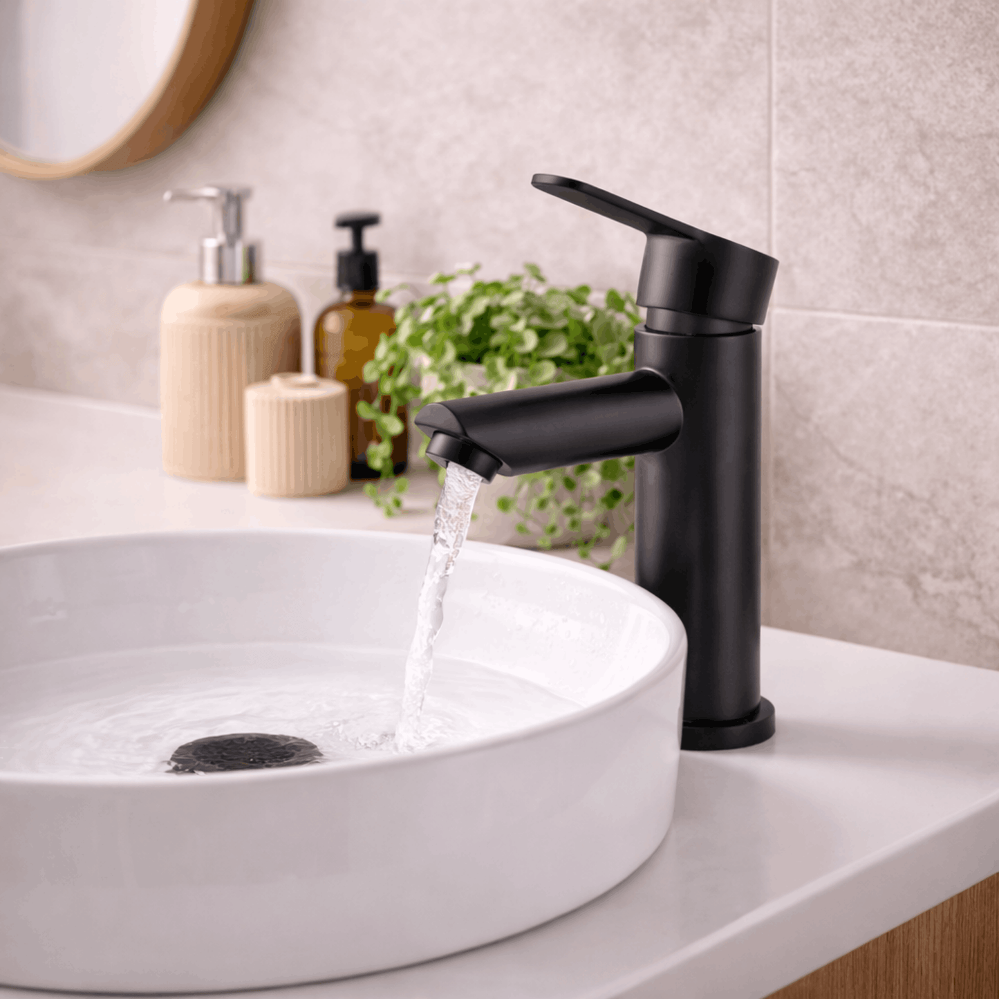 Moderne zwarte wastafelkraan voor warm en koud water met stromend water in een ronde witte wasbak in een stijlvolle badkamer.