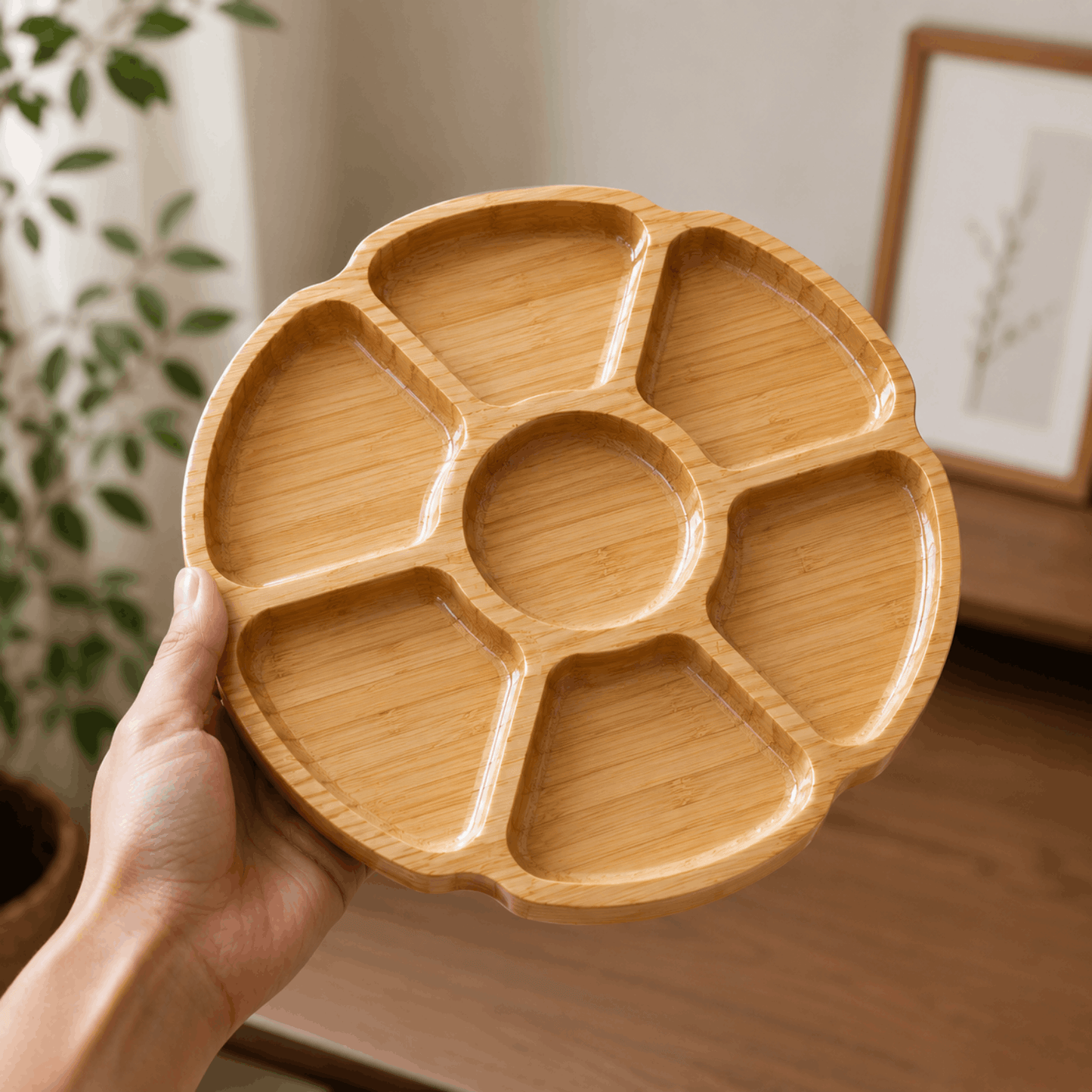 Ronde bamboe borrelplank met meerdere vakken, vastgehouden in een hand.
