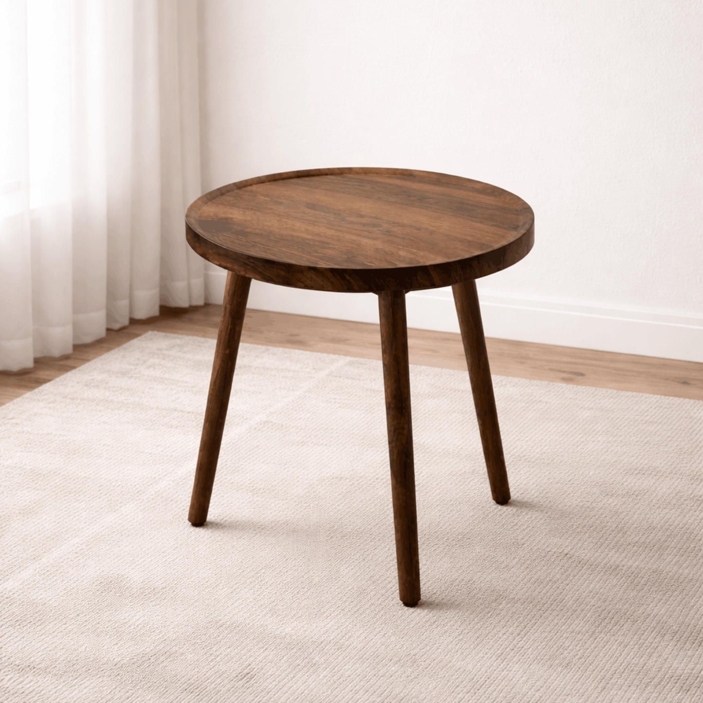 Ronde houten bijzettafel met drie poten geplaatst op een licht tapijt in een minimalistische kamer.