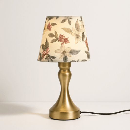 Vintage messing tafellamp met stoffen bloemenkap, verspreidt warm licht en voegt retro charme toe.