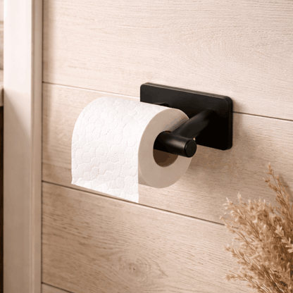 Zwarte wandgemonteerde toiletrolhouder met een minimalistisch ontwerp, bevestigd op een houten wand in de badkamer.
