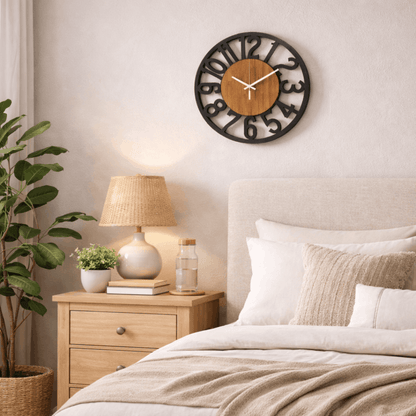 Ronde wandklok met houten kern en zwarte cijfers, hangend aan de muur boven een nachtkastje in een rustige slaapkamer.