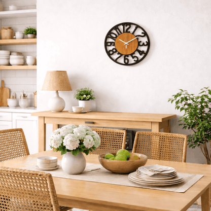 Ronde wandklok met zwarte rand en houten binnenzijde, hangend aan een witte muur in een lichte eetkamer.