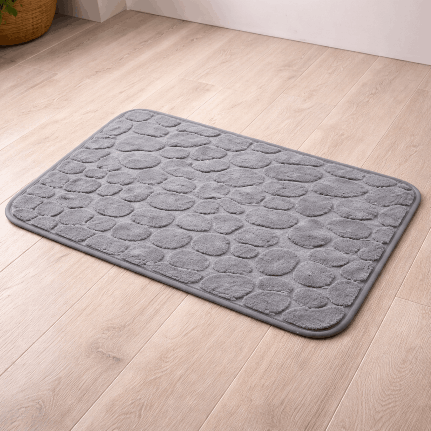 Zachte grijze badmat met steenpatroonstructuur en antislip onderkant, ideaal voor gebruik naast douche of bad.