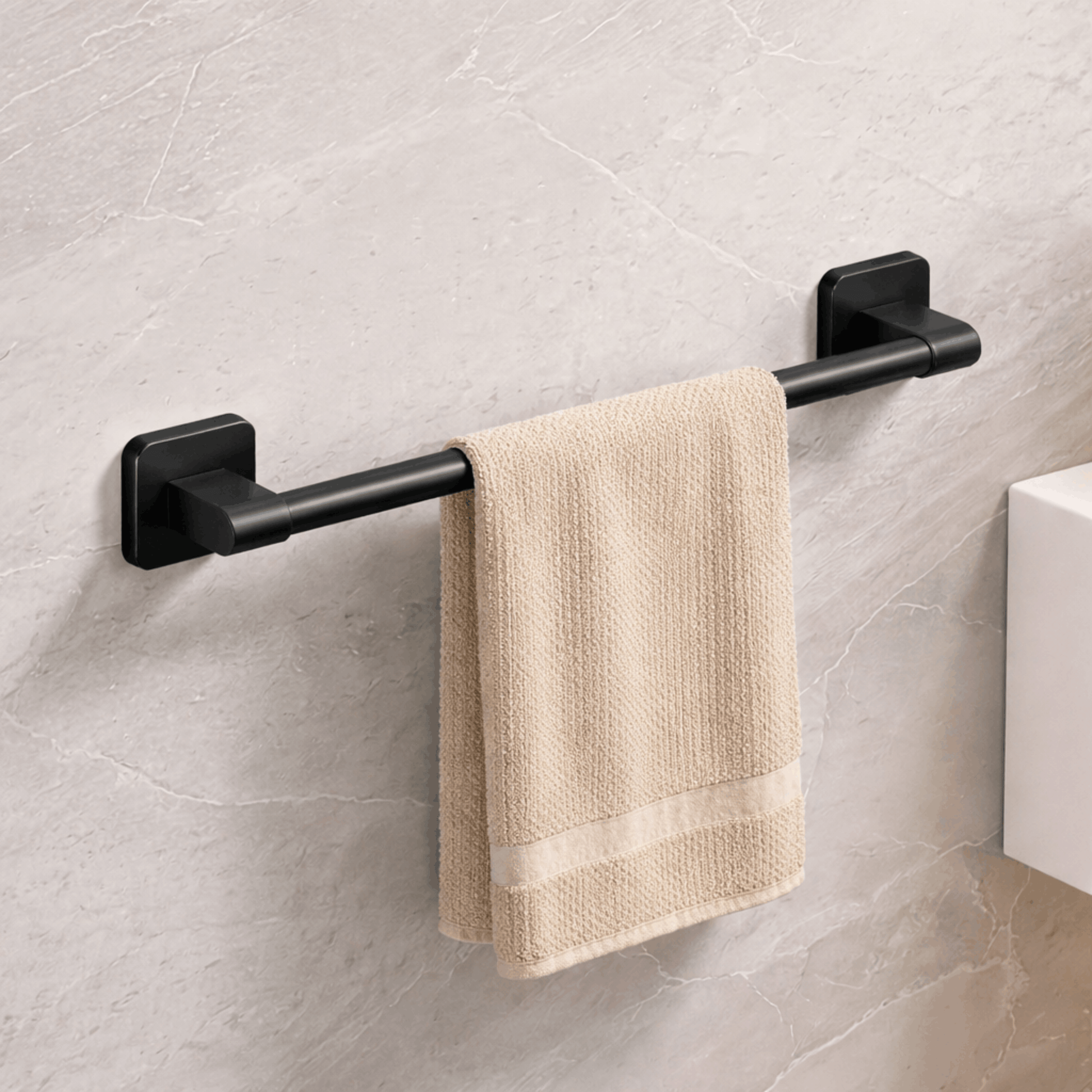 Zwart metalen handdoekrek aan de badkamerwand met een beige handdoek eroverheen.