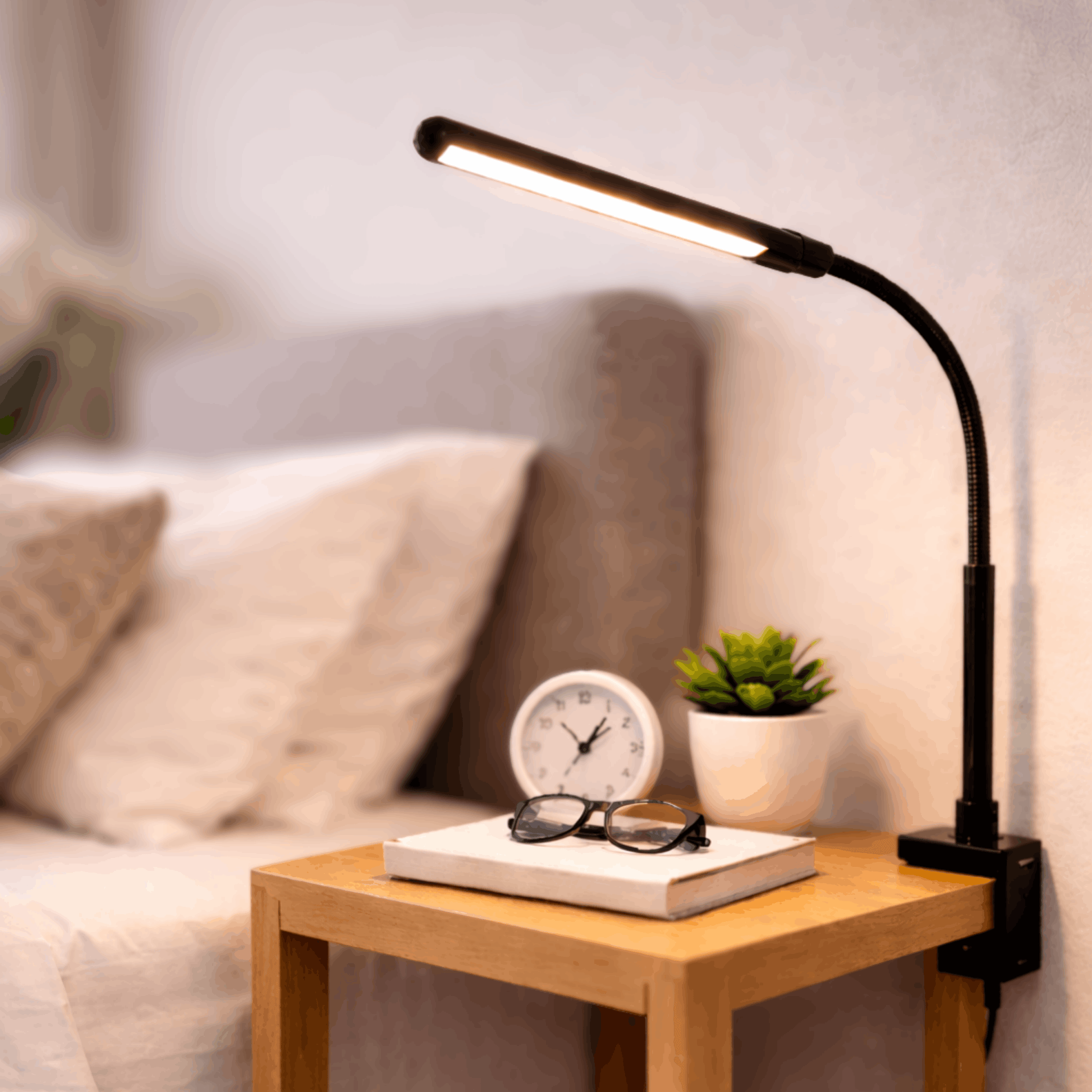 Zwarte bureaulamp met flexibele arm en smalle lichtbalk, bevestigd aan een nachtkastje naast een bed voor gericht licht.