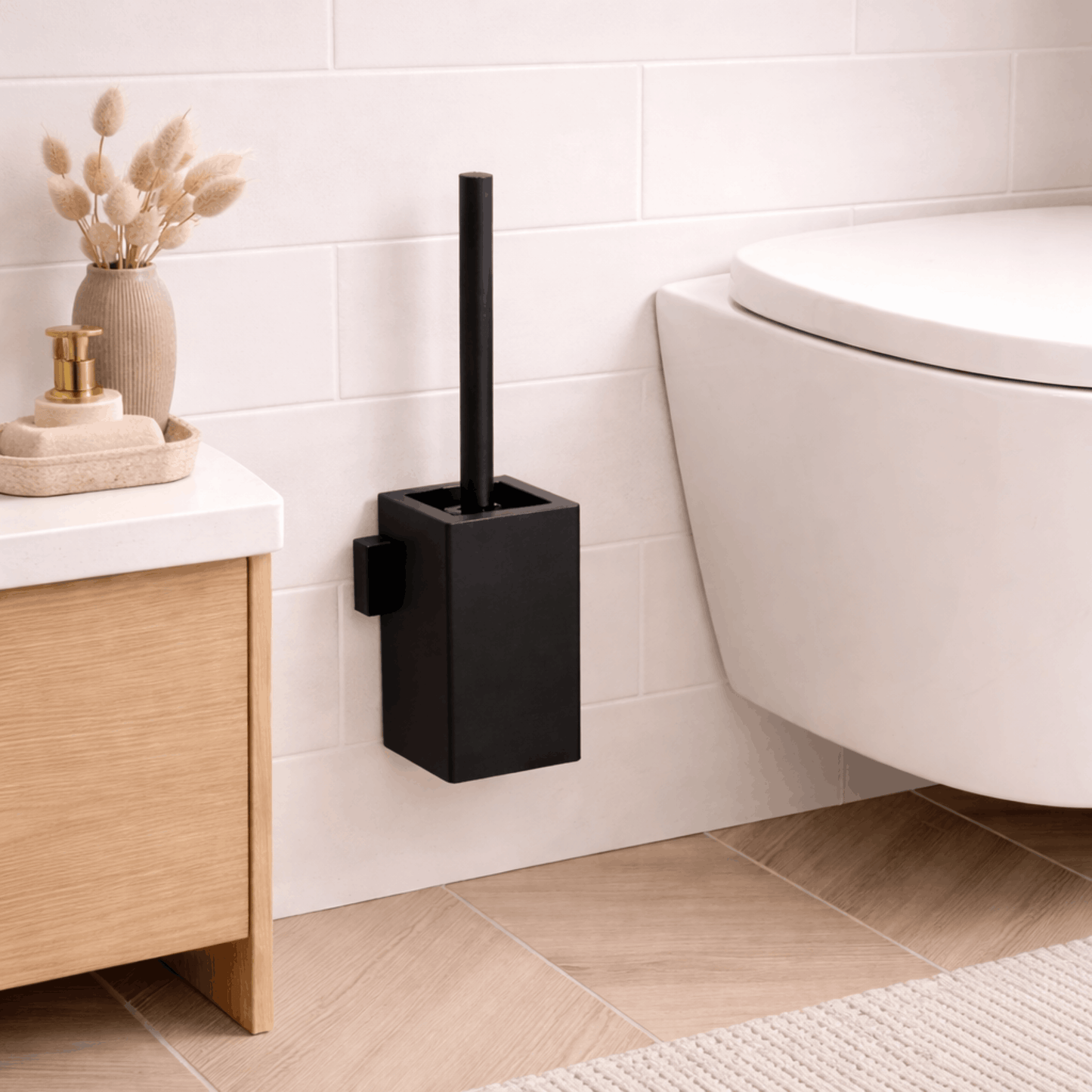 Zwarte wc borstel met vierkante houder voor wandmontage, geplaatst naast een toilet in een moderne badkamer.